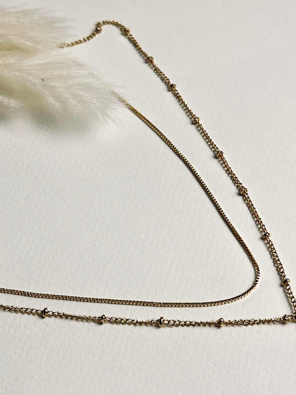 Serena — Gold Box Chain Necklace from the Timeless Grace collection, layered with another delicate gold necklace on a model. The thin gold-plated brass chains create a graceful, sophisticated look, showcasing versatile styling while symbolizing balance, elegance, and subtle self-expression.