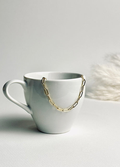 Gloria – Gold Paperclip Necklace from the Timeless Grace collection, an 18k gold-filled 16-inch chain. The delicate links catch the light, reflecting timeless elegance and quiet confidence — a reminder to carry your grace with ease and let your inner glow shine.