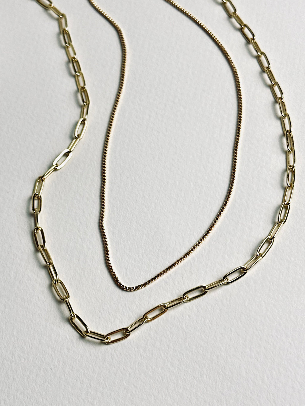Gloria – Gold Paperclip Necklace layered with a dainty gold box chain necklace from the Timeless Grace collection, 18k gold-filled. The contrast of bold and delicate chains reflects balance — a blend of strength and softness that celebrates effortless elegance and inner grace.