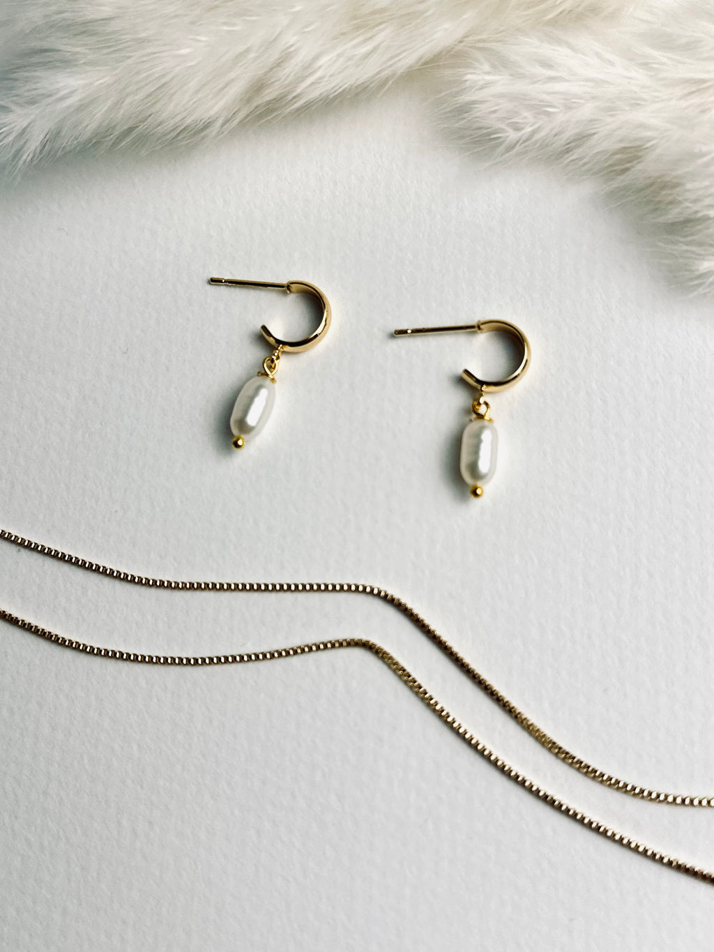 Single pearl displayed on a delicate C-shape earring post, showcasing its minimalist elegance. The soft luster of the pearl conveys timeless beauty, subtle sophistication, and refined grace.