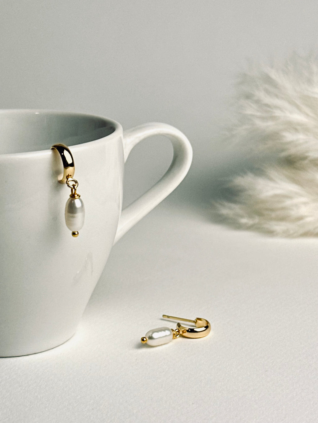 Single pearl displayed on a delicate C-shape earring post, showcasing its minimalist elegance. The soft luster of the pearl conveys timeless beauty, subtle sophistication, and refined grace.