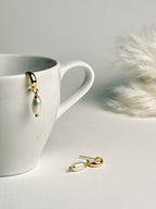 Single pearl displayed on a delicate C-shape earring post, showcasing its minimalist elegance. The soft luster of the pearl conveys timeless beauty, subtle sophistication, and refined grace.