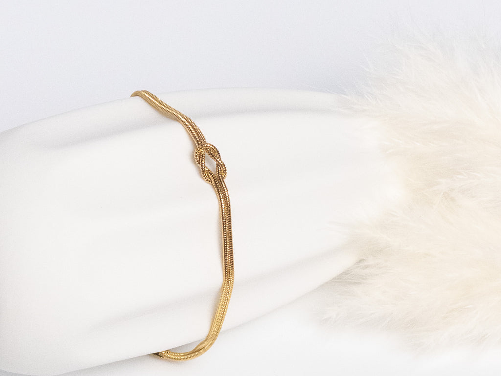 Grace Knot Bracelet gold infinity knot bracelet front view on vase showing knot detail