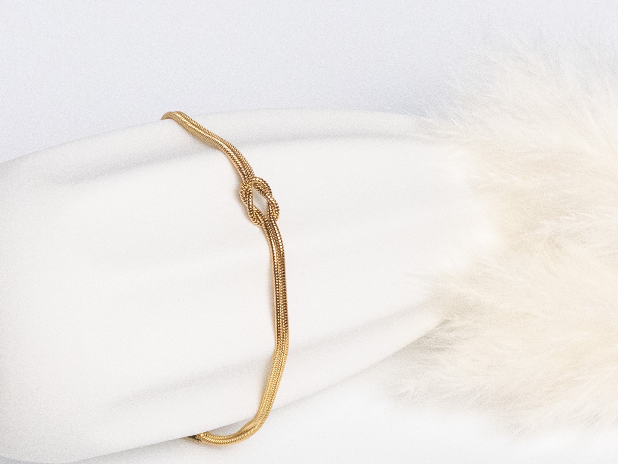 Grace Knot Bracelet gold infinity knot bracelet front view on vase showing knot detail