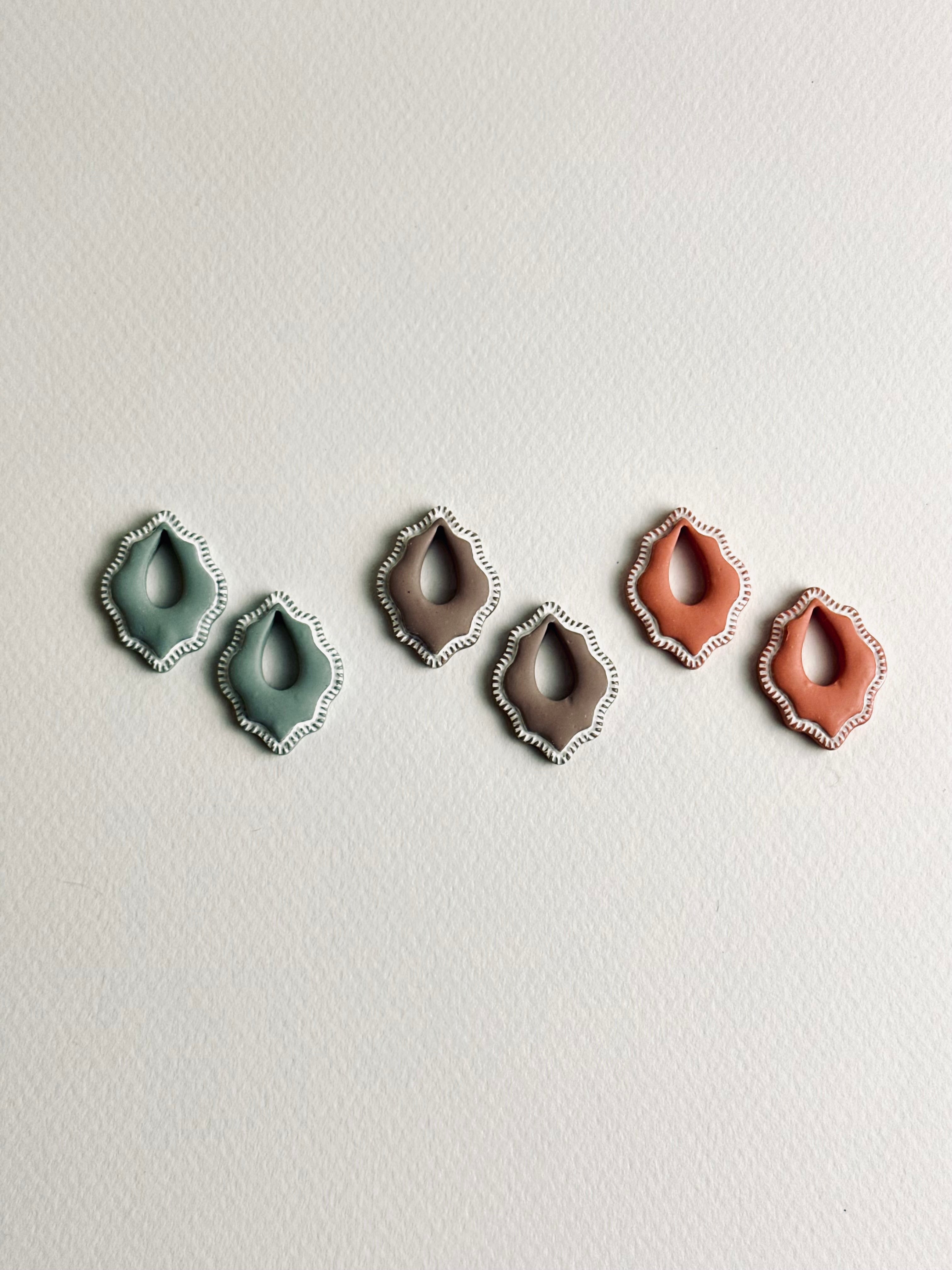 Three Valeria polymer clay charms in cocoa, soft terra, and sage mist, displayed on Versilana hoops in gold and silver tones — elegant, minimalist earrings with soft earthy colors.