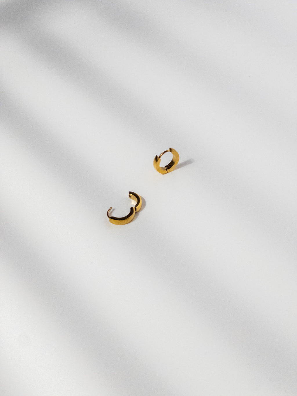 Ease Hoop Earrings shown in detail, with one earring clasp open and the other displayed at an angle.