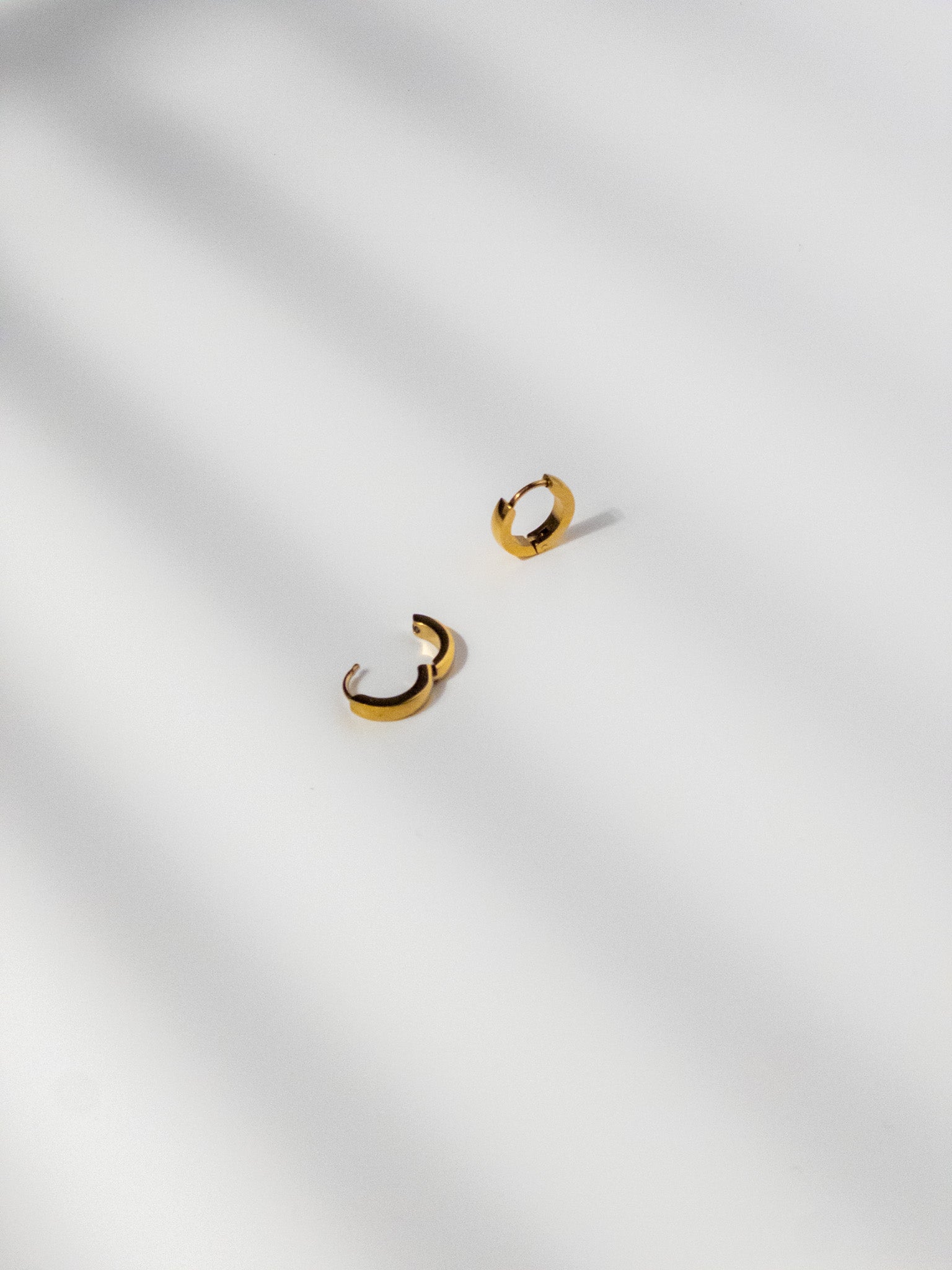 Ease Hoop Earrings shown in detail, with one earring clasp open and the other displayed at an angle.