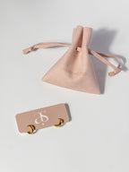 Ease Hoop Earrings displayed on a jewelry card with a matching jewelry pouch for storage and gifting.