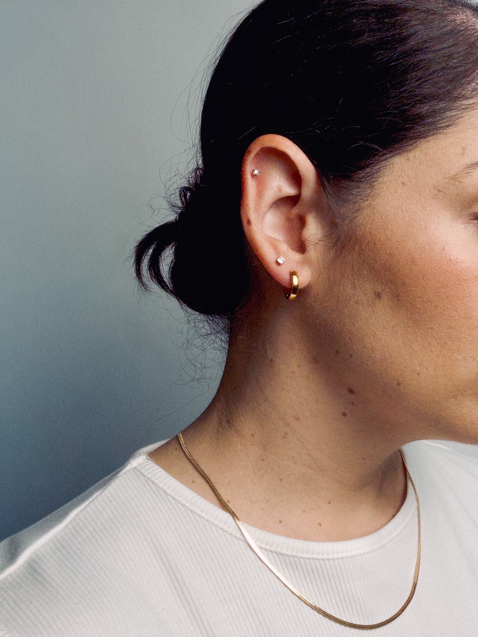 Model wearing Ease Hoop Earrings paired with the Lumen Chain necklace in a minimalist gold jewelry layered look.