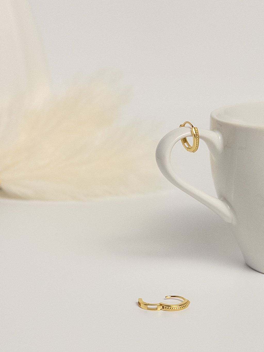 Grace Thread rope hoop earrings flat lay with one earring open to show clasp and one displayed on cup handle