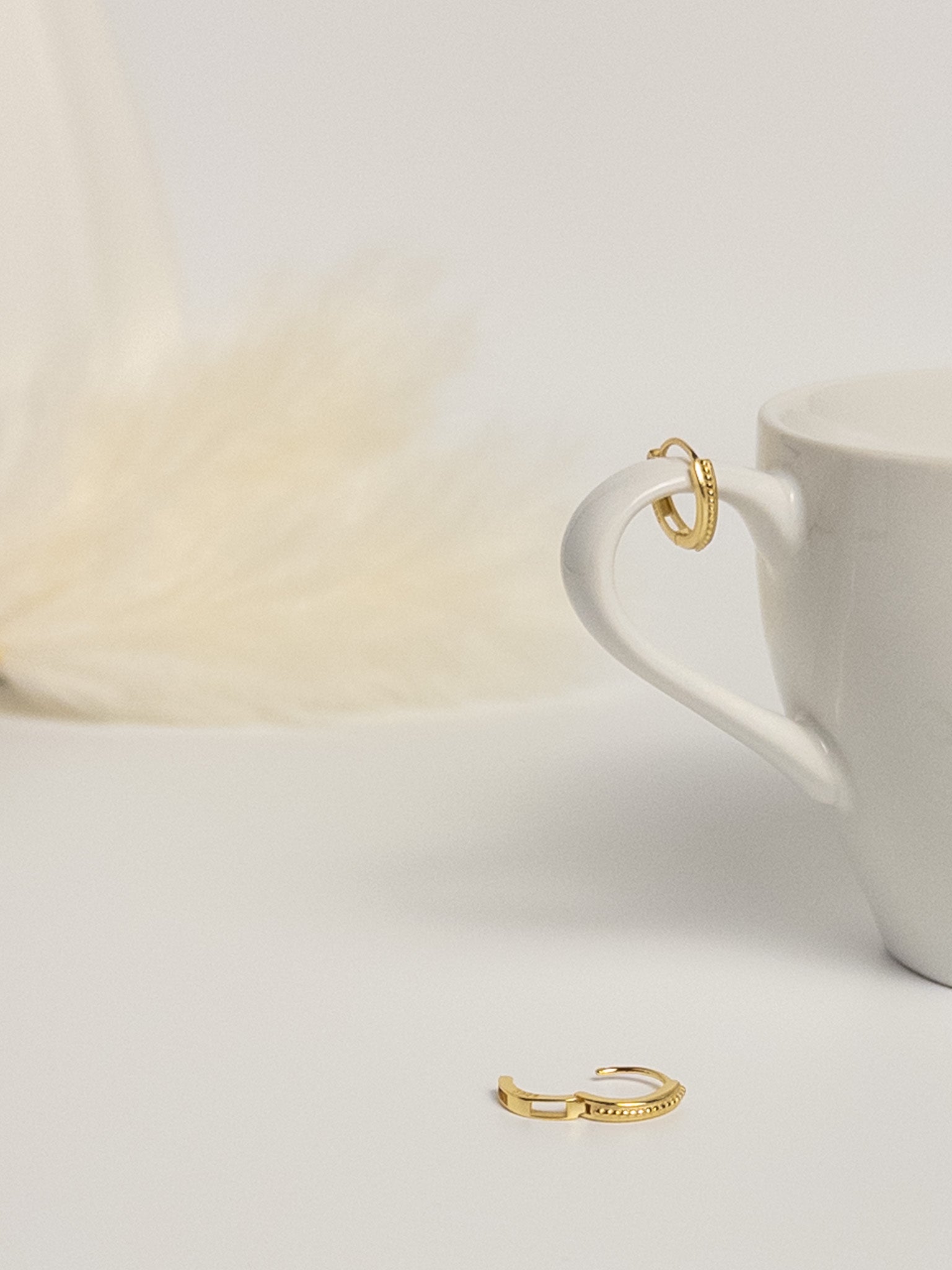 Grace Thread rope hoop earrings flat lay with one earring open to show clasp and one displayed on cup handle