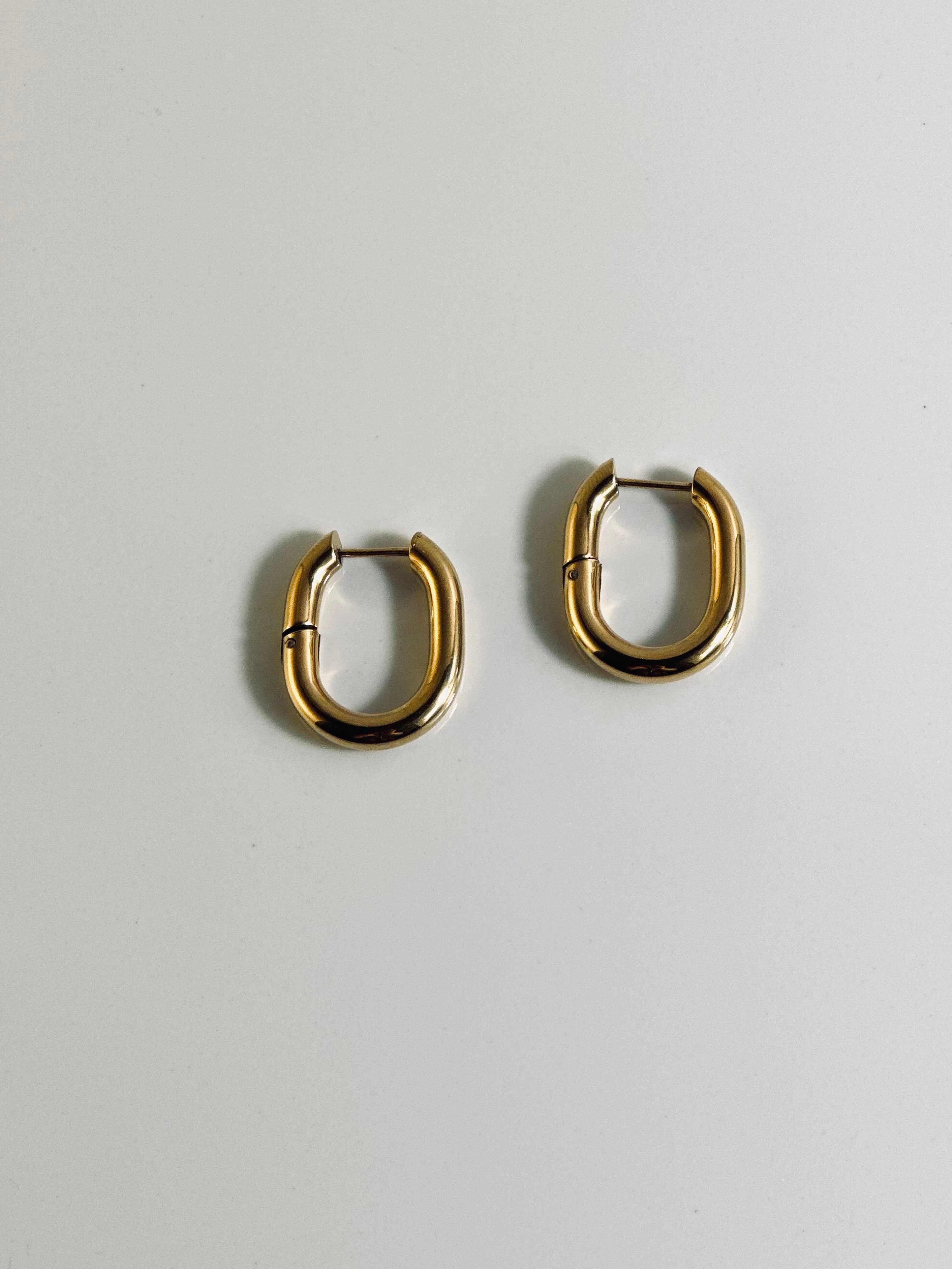 Vera Hoop earrings from the “Timeless Grace” collection displayed flat, showcasing their bold 1-inch 18k gold-plated design. The chunky shape and radiant finish reflect strength and elegance, made to last with hypoallergenic and tarnish-resistant quality.
