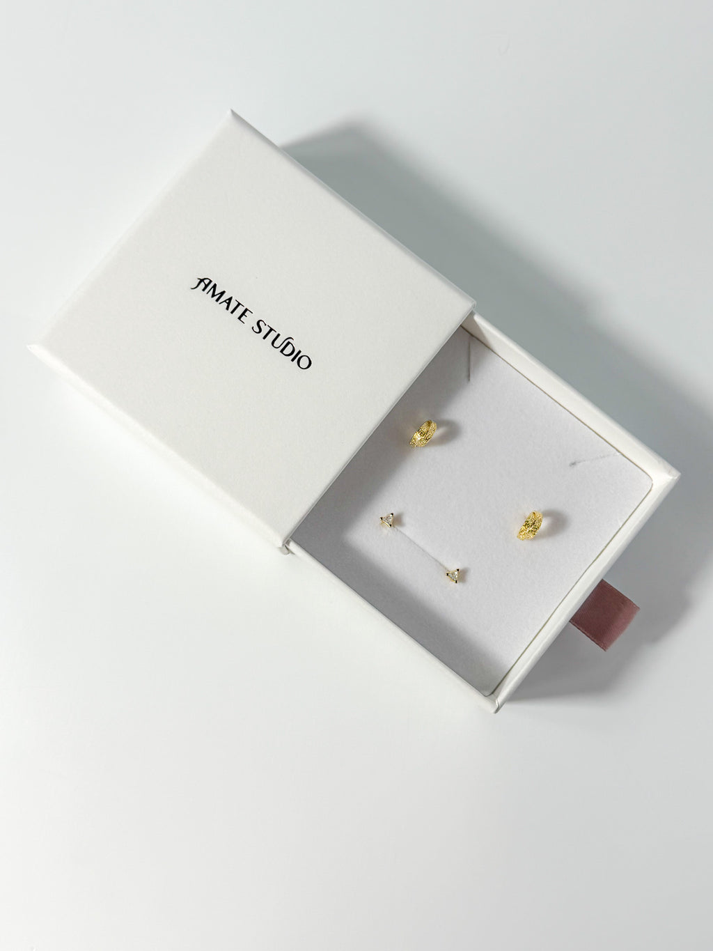Lucía Set triangle stud and textured C-hoop earrings displayed on a branded drawer jewelry box