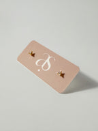 Lucía Studs tiny triangle CZ stud earrings displayed on an earring card