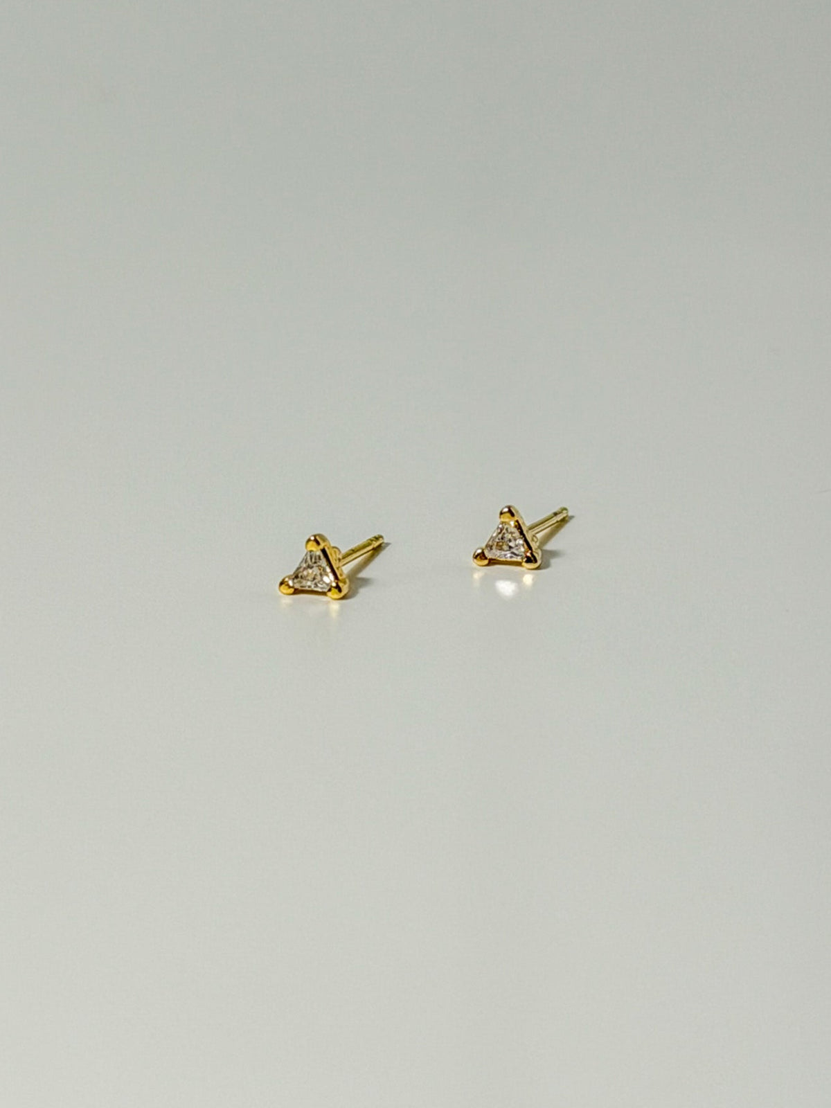 Lucía Studs tiny triangle CZ stud earrings in a flatlay