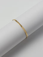 Lumen Bracelet front view displayed on a round bracelet stand, featuring a minimalist 18k gold filled snake chain design from the Weightless Collection.