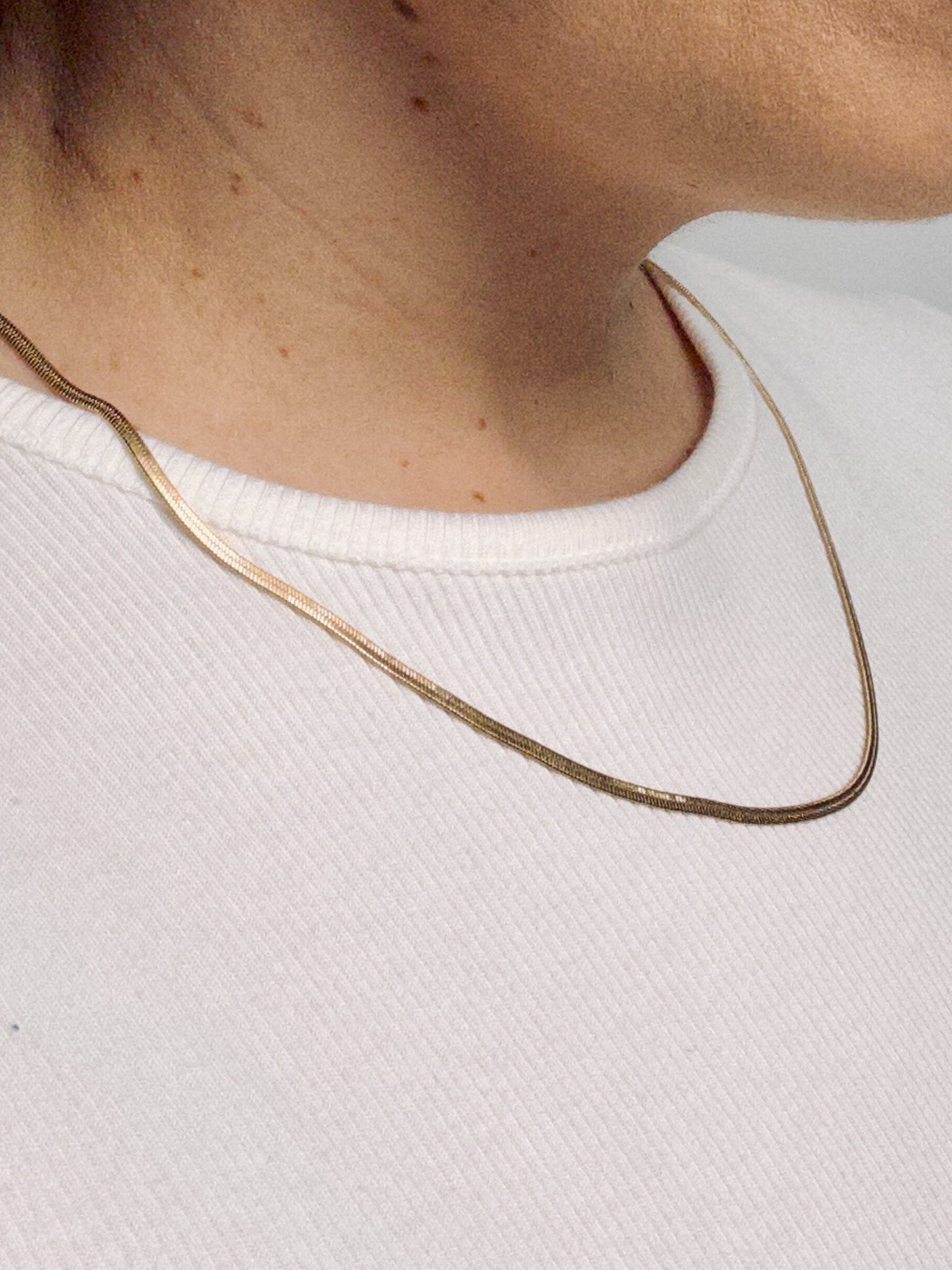 Model wearing the Lumen Chain snake necklace in a minimalist gold jewelry style.