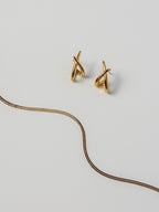 Amate Studio Lumen Studs and Lumen Chain necklace in 18k gold filled jewelry displayed in a flat lay on a neutral background, featuring a flowing wavy chain design and minimalist everyday style.