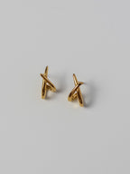 Lumen Studs gold crossover stud earrings featuring a minimalist intertwined design for everyday wear.