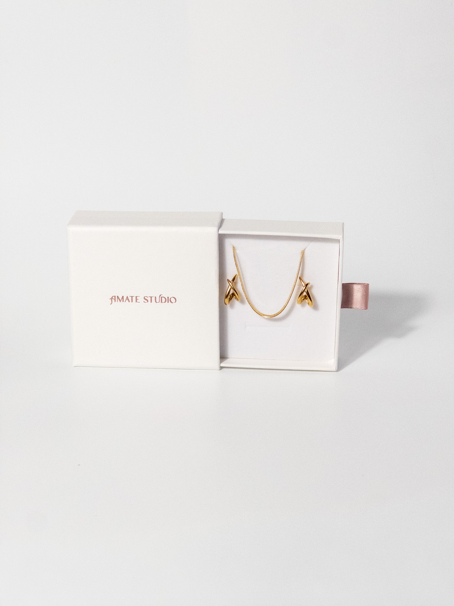 Amate Studio Lumen Studs and Lumen Chain necklace displayed in a fully opened drawer-style jewelry box, showcasing the 18k gold filled jewelry and premium packaging presentation.