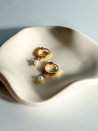 Meli gold-filled hoops with single freshwater pearls, angled detail view on a jewelry tray.