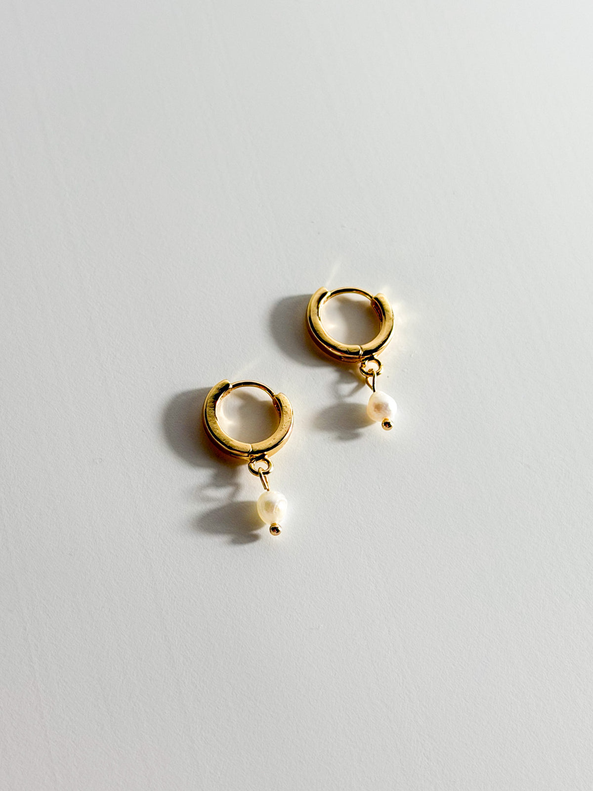 Meli gold-filled hoops with a single freshwater pearl, photographed from the front.